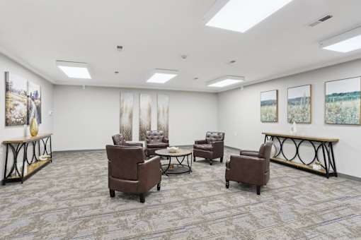 A room with a grey carpet and brown leather chairs.