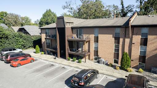 an aerial view of a brick apartment building with cars in a parking lot
