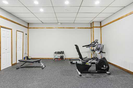 A room with a treadmill, rowing machine, and exercise bike.