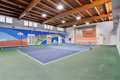 A tennis court with a blue and green surface and a wooden ceiling.