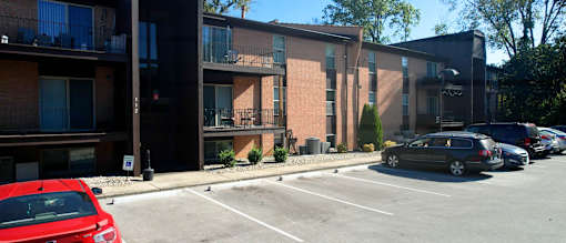 a parking lot in front of a brick building with cars parked