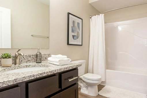 A bathroom with a white toilet, sink, and shower.