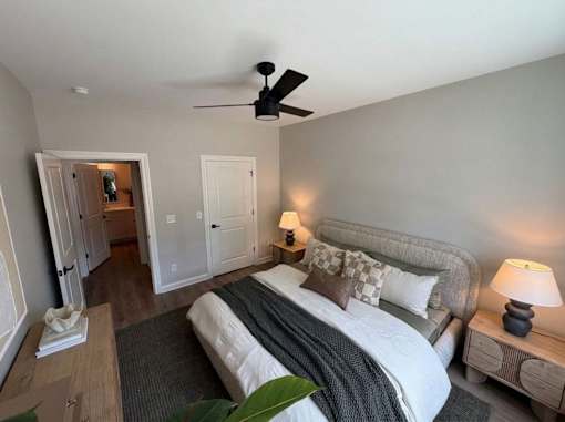 A bedroom with a large bed and a ceiling fan.