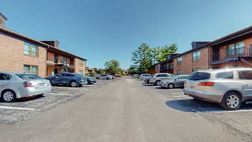 a parking lot filled with cars in front of apartment buildings