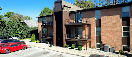 a brick apartment building with a red car parked in front of it