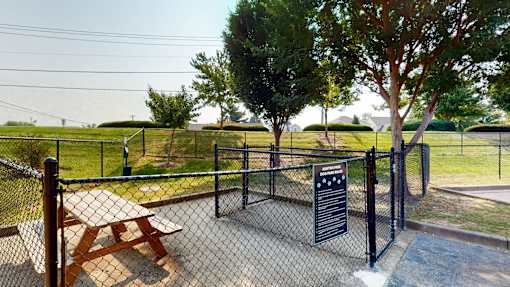 A picnic table is surrounded by a fence and a sign is posted on the fence.