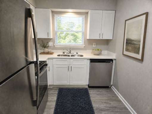 A modern kitchen with white cabinets and a stainless steel refrigerator.