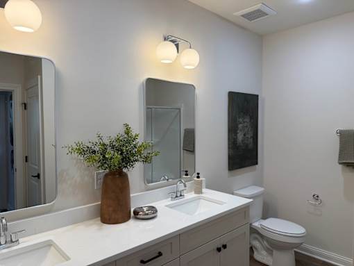 A bathroom with a white countertop and a brown vase with green plants.