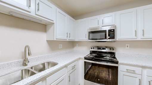 A kitchen with white cabinets and a stove top oven.