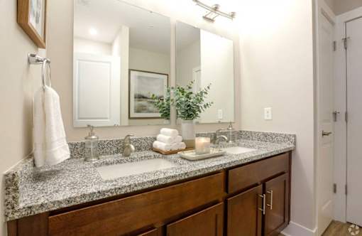 A bathroom with a granite countertop and a large mirror.