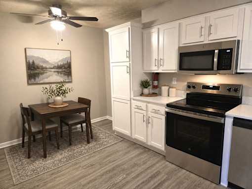A kitchen with a table and chairs and a painting of a lake on the wall.