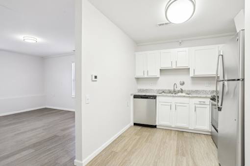 A kitchen with white cabinets and a refrigerator.