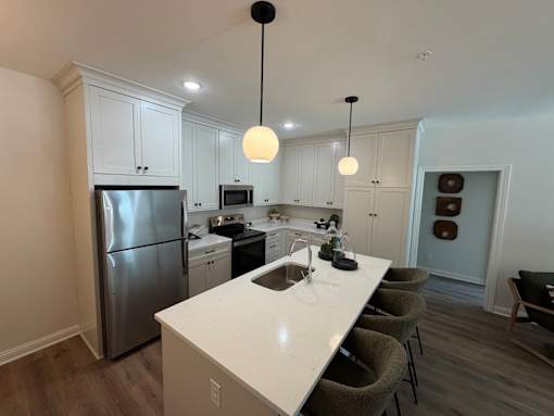 A modern kitchen with a white countertop and stainless steel appliances.