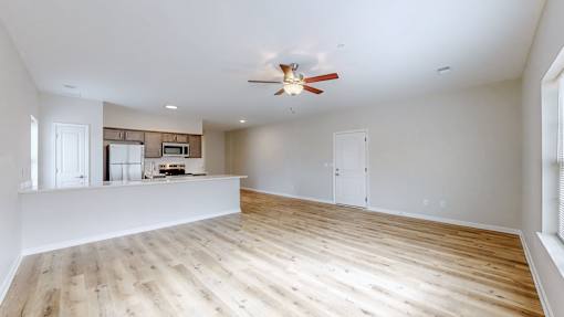 A spacious room with wooden flooring and a ceiling fan.