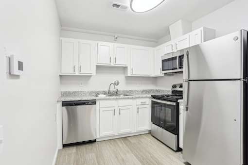 A kitchen with white cabinets and a black fridge.