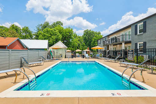 A swimming pool surrounded by a metal fence and a building in the background.