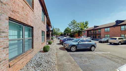 a parking lot in front of a brick building with cars parked