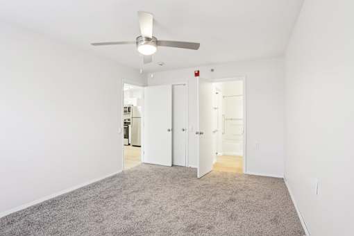 A room with a ceiling fan and carpeted floor.