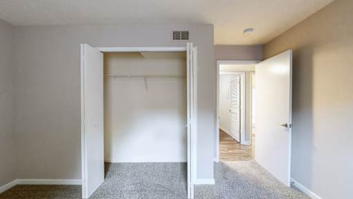 A room with a carpeted floor and two open doors.