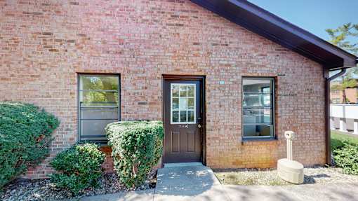 the front of a brick building with a brown door