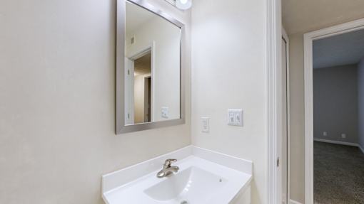 A white sink in a bathroom with a mirror above it.