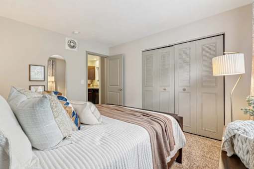 A bedroom with a bed, dresser and closet  at Avenue in the Highlands Apartments in Louisville