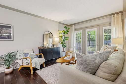 An apartment living room with a couch, chair, and potted plant in Louisville, KY