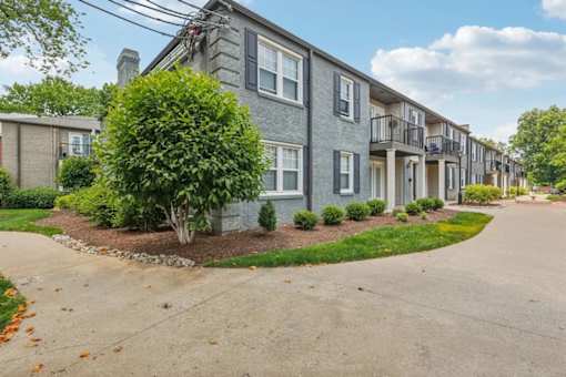 A gray colored apartment building with trees and green grass in Louisville, KY