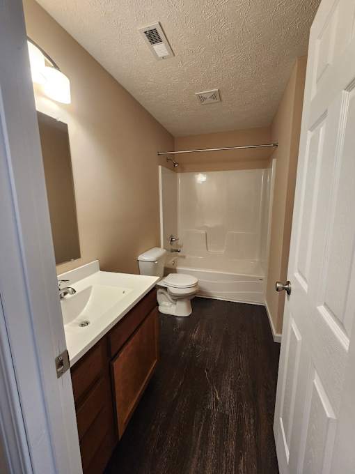 A bathroom with a toilet, sink, and shower.