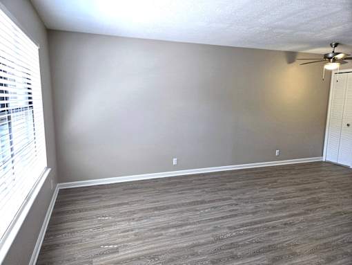A room with a ceiling fan and wooden flooring.
