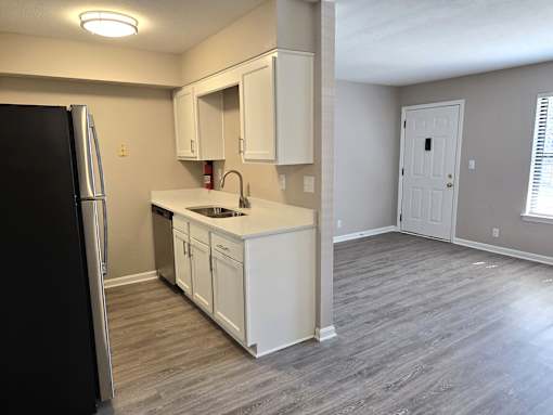 A kitchen with a black refrigerator and white cabinets.