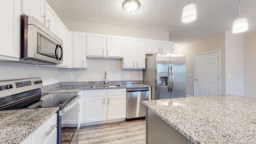 A kitchen with white cabinets and granite countertops.