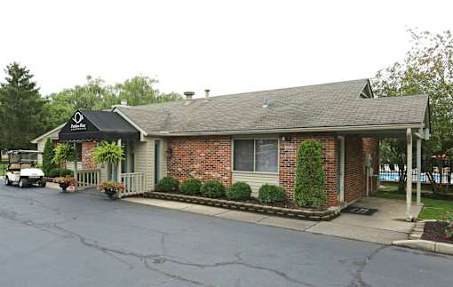 A small brick building with a black awning and a white golf cart parked in front.