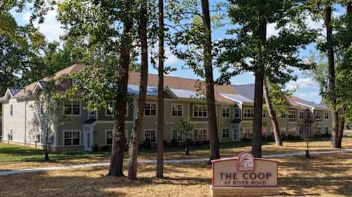 A sign that says "The Coop at River Road" is in front of a building.