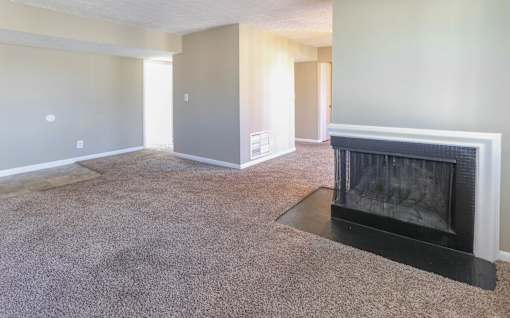 A living room with a fireplace and carpeted floor.