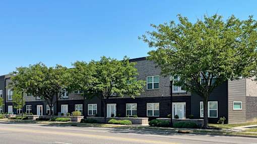 A row of modern houses with trees in front.