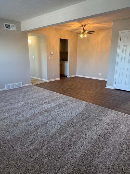 A room with a striped carpet and a ceiling fan.