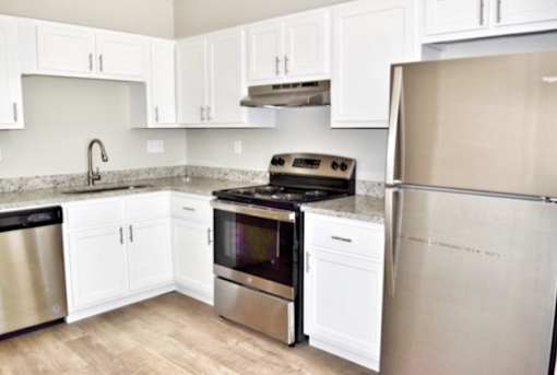 A kitchen with white cabinets and a stainless steel refrigerator.