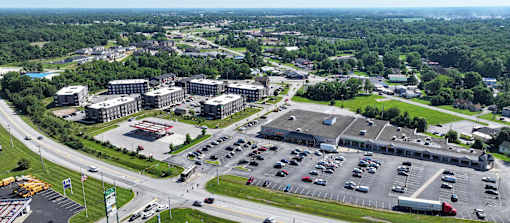 A large parking lot is surrounded by buildings and a highway.