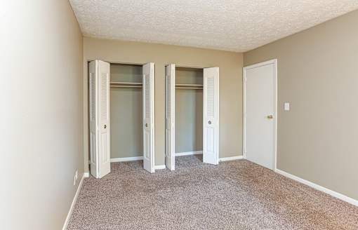 A room with a carpeted floor and a white door.
