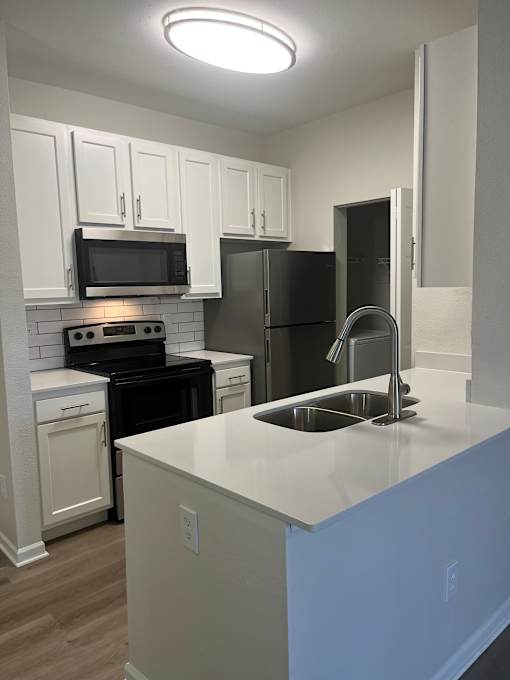 A kitchen with white cabinets and black appliances.
