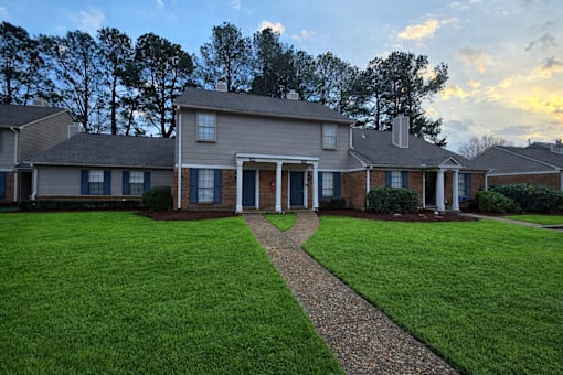 A house with a green lawn and a stone pathway leading to the front door.