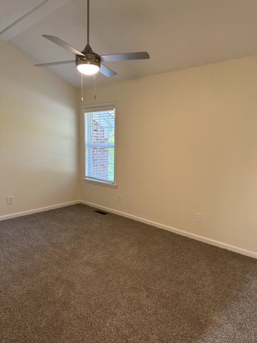 a ceiling fan in the corner of a room with a window