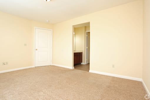 a empty living room with a door to a bathroom