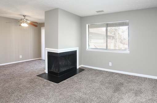 A living room with a fireplace and a ceiling fan.