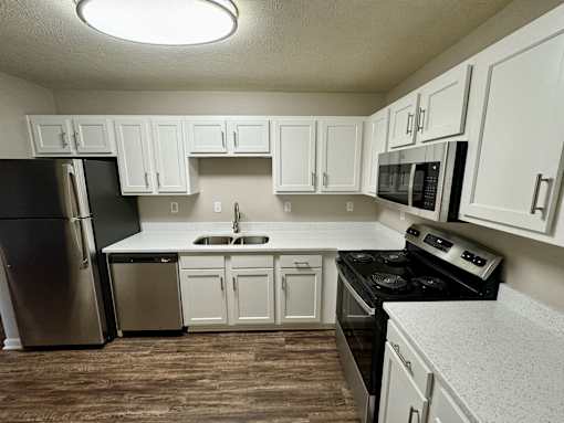A kitchen with white cabinets and black appliances.