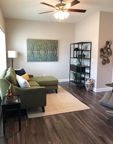 A living room with a green couch and a painting on the wall.