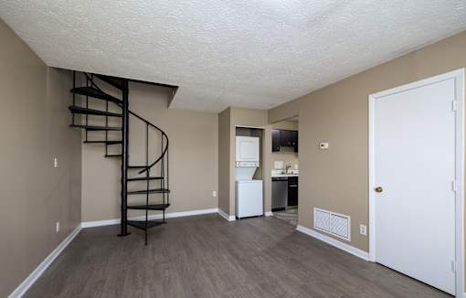 A room with a spiral staircase and a white door.