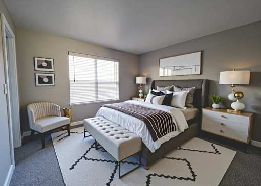 A bedroom with a large bed, a chair, and a nightstand.