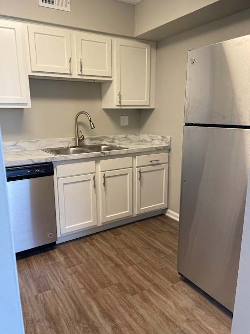 A kitchen with white cabinets and a stainless steel refrigerator.